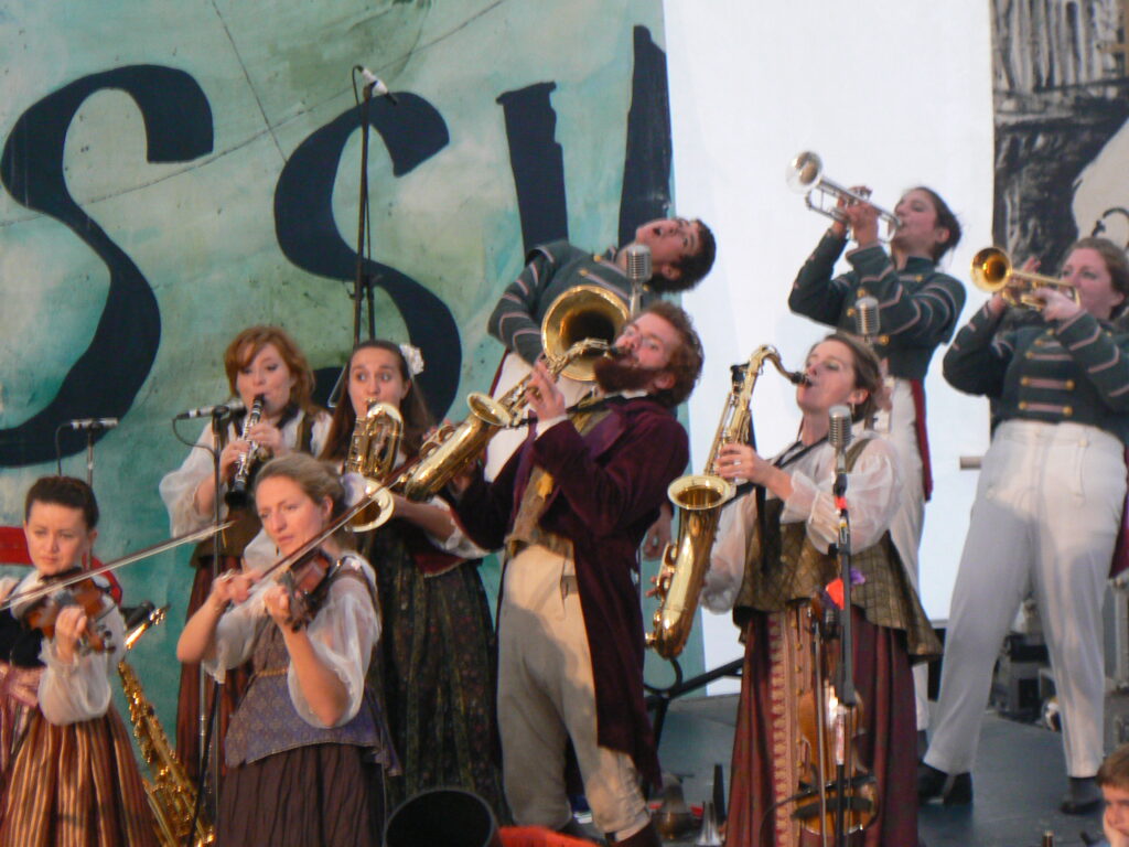 Circus band performing playing violins, saxophones and brass instruments. Musicians in period costume